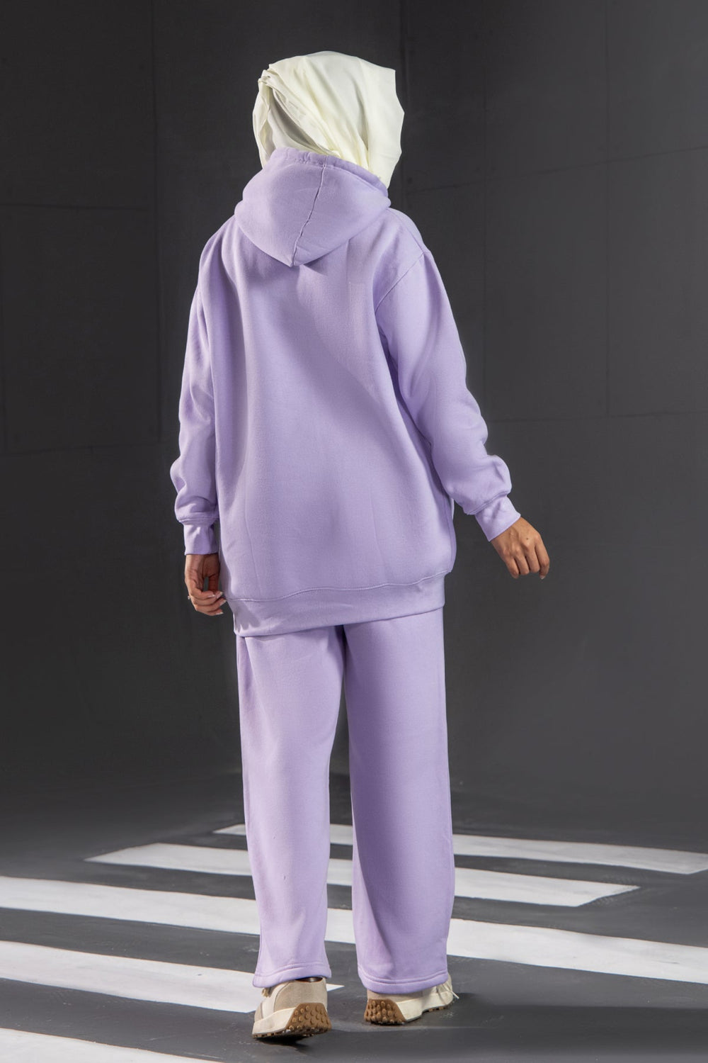 Person wearing a lavender tracksuit with 'TIRED' text on a black background